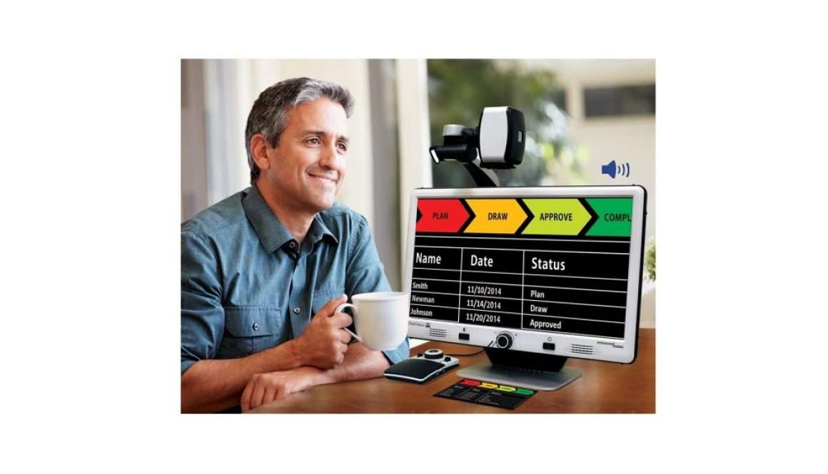 A man using a DaVinci Pro Magnifier at home to view documents on screen with a color-coded task display.