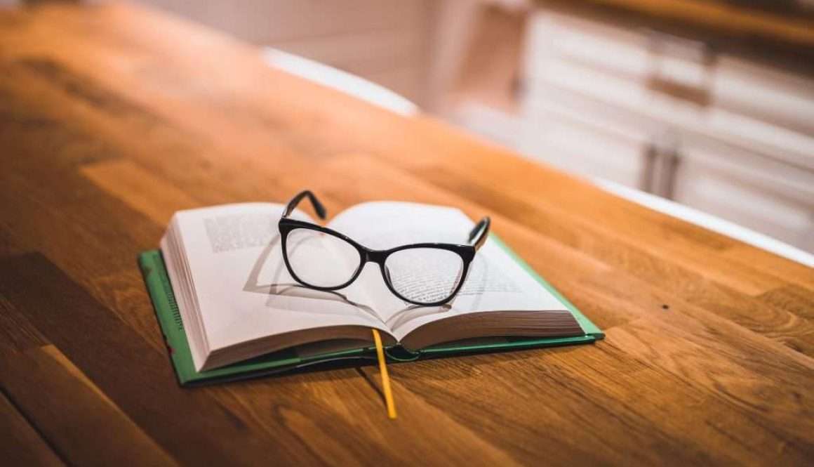 Open book and glasses on table. Book and glasses.